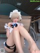 A woman in a maid outfit sitting on the ground.