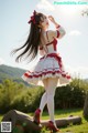 A woman in a red and white dress standing on a log.