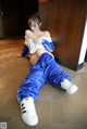 A woman in a blue and white outfit is sitting on the floor.