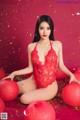 A woman in a red lingerie sitting on a red background.