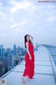 A woman in a red dress standing on top of a building.