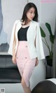 a woman in a white jacket and pink skirt posing for a picture