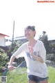 A woman is playing with a hose in the grass.