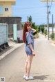 A woman standing on the side of a road with her hands on her head.